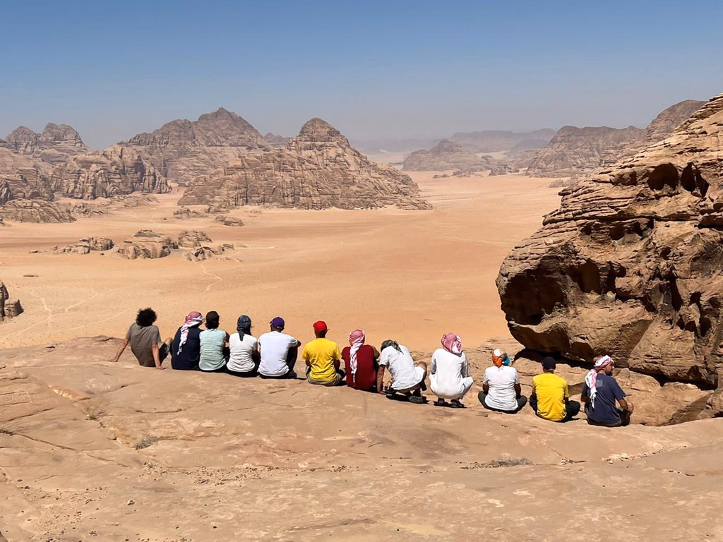 Guests sitting on a rock and admiring Wadi Rum Desert in Jordan