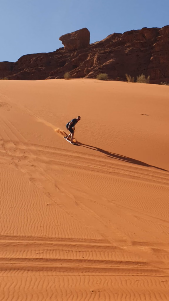 Sandboarding on a red dune in Wadi Rum, Jordan