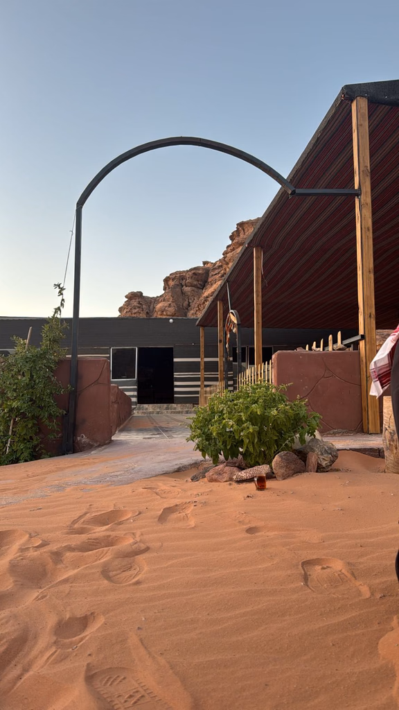 Wooden camp building and arched entrance beside desert plants