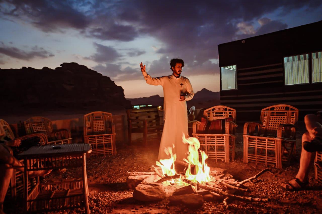 Bedouin guide telling stories to our guests at our camp campfire, Wadi Rum, Jordan