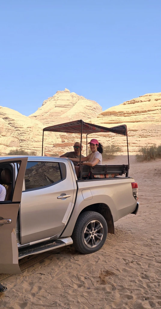 Jeep parked at a desert tour stop beneath Wadi Rum cliffs
